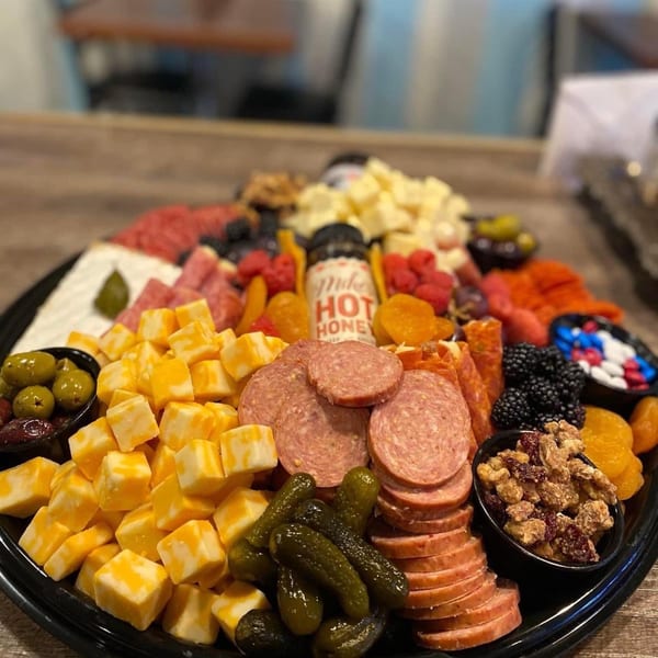 A large charcuterie board from Molli's Cafe with cheeses, meats, fruits, nuts, and pickles.